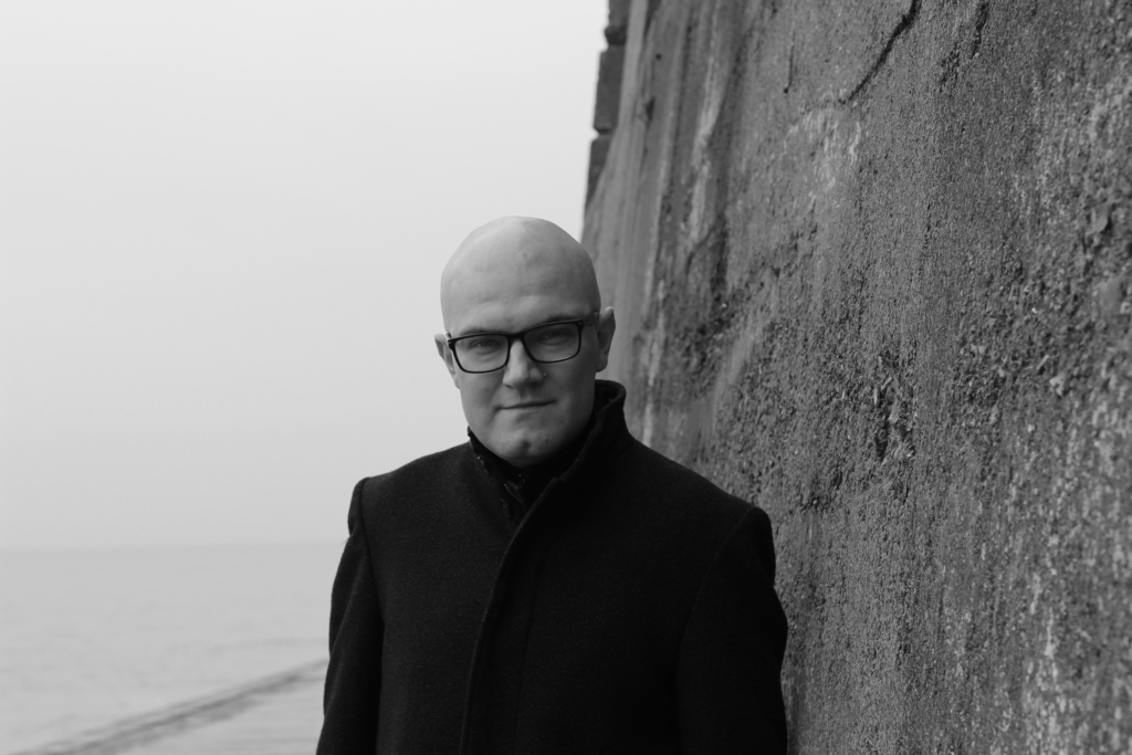 black and white photo of Martin Eve standing next to a seawall